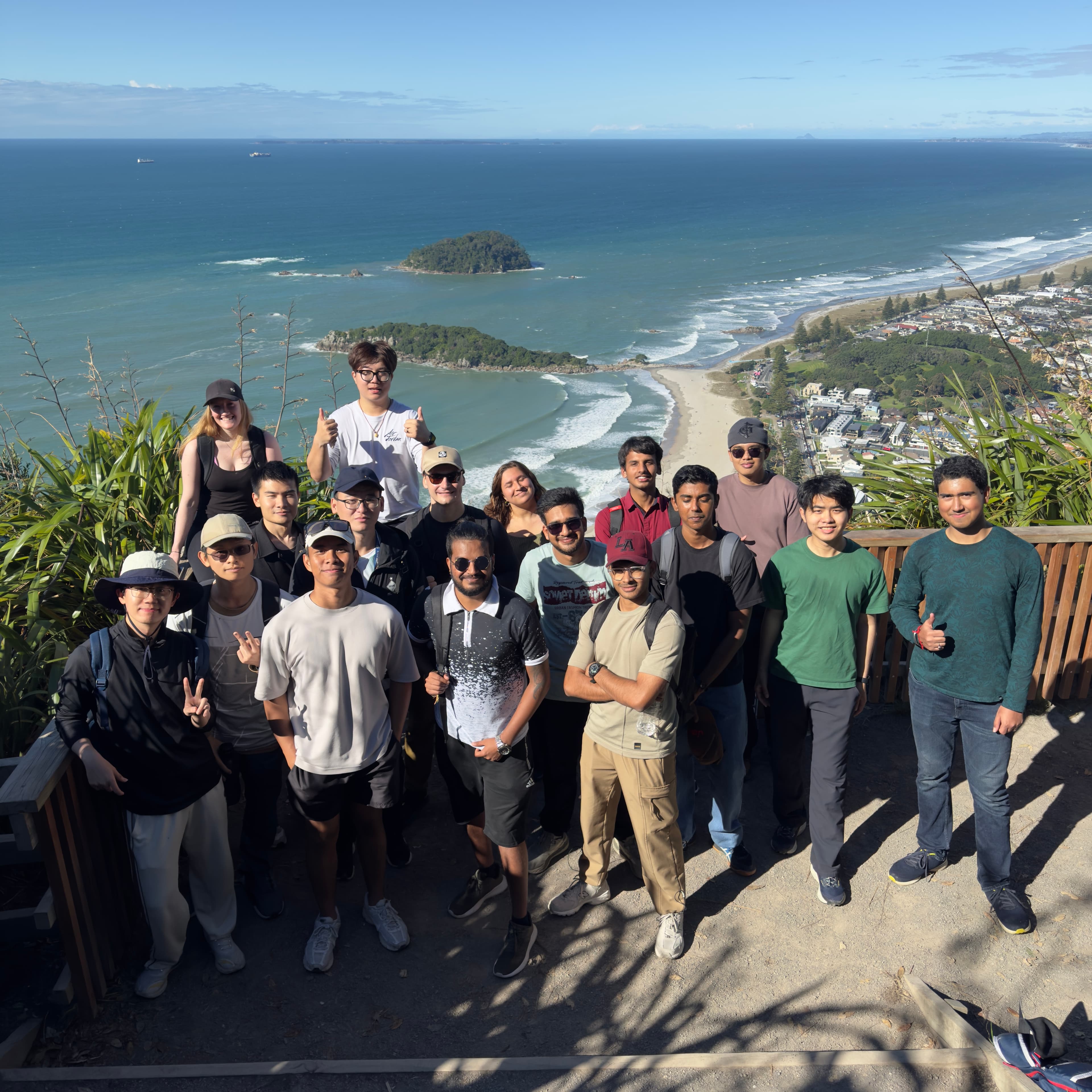 A large group of residents at a coastal summit lookout, with the beach and ocean behind them.